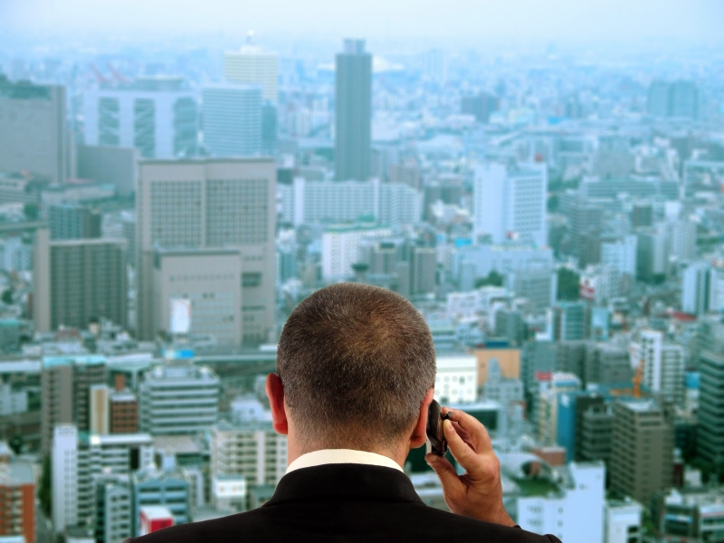 Man on cell phone looking out over the city skyline