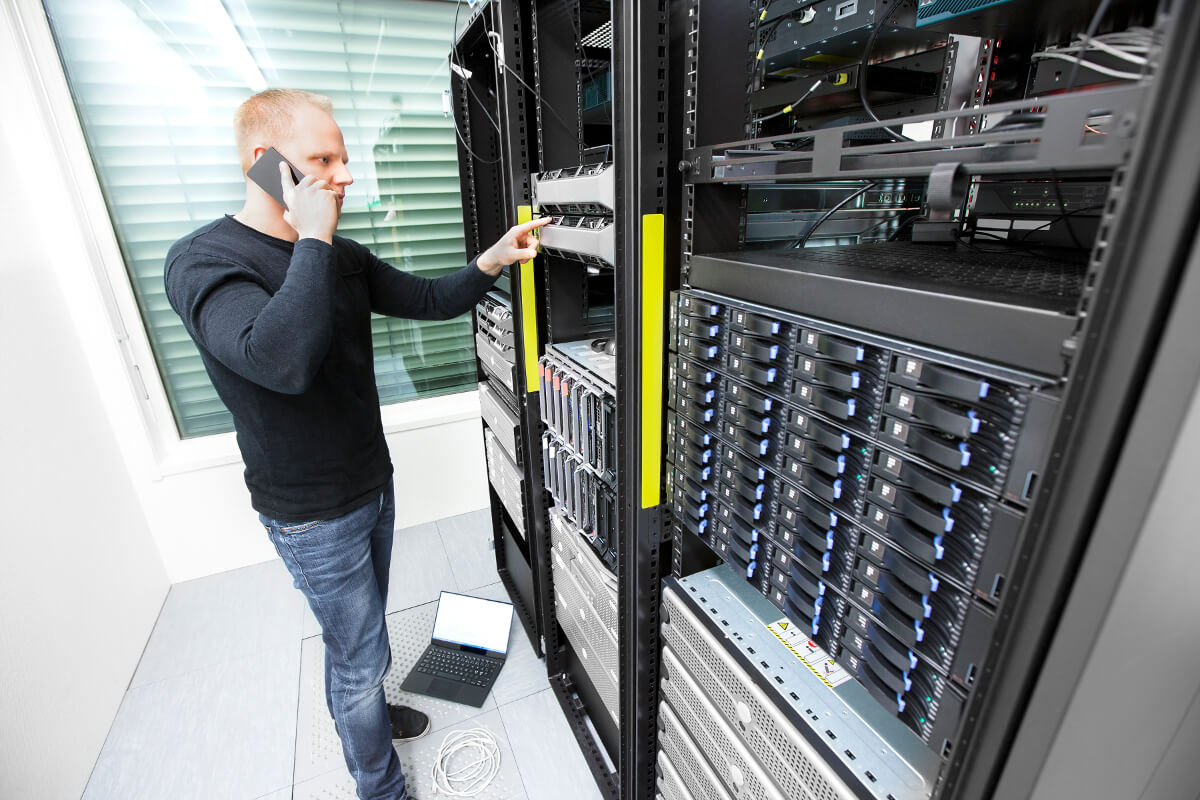 Man on the phone will pointing at servers in a server room