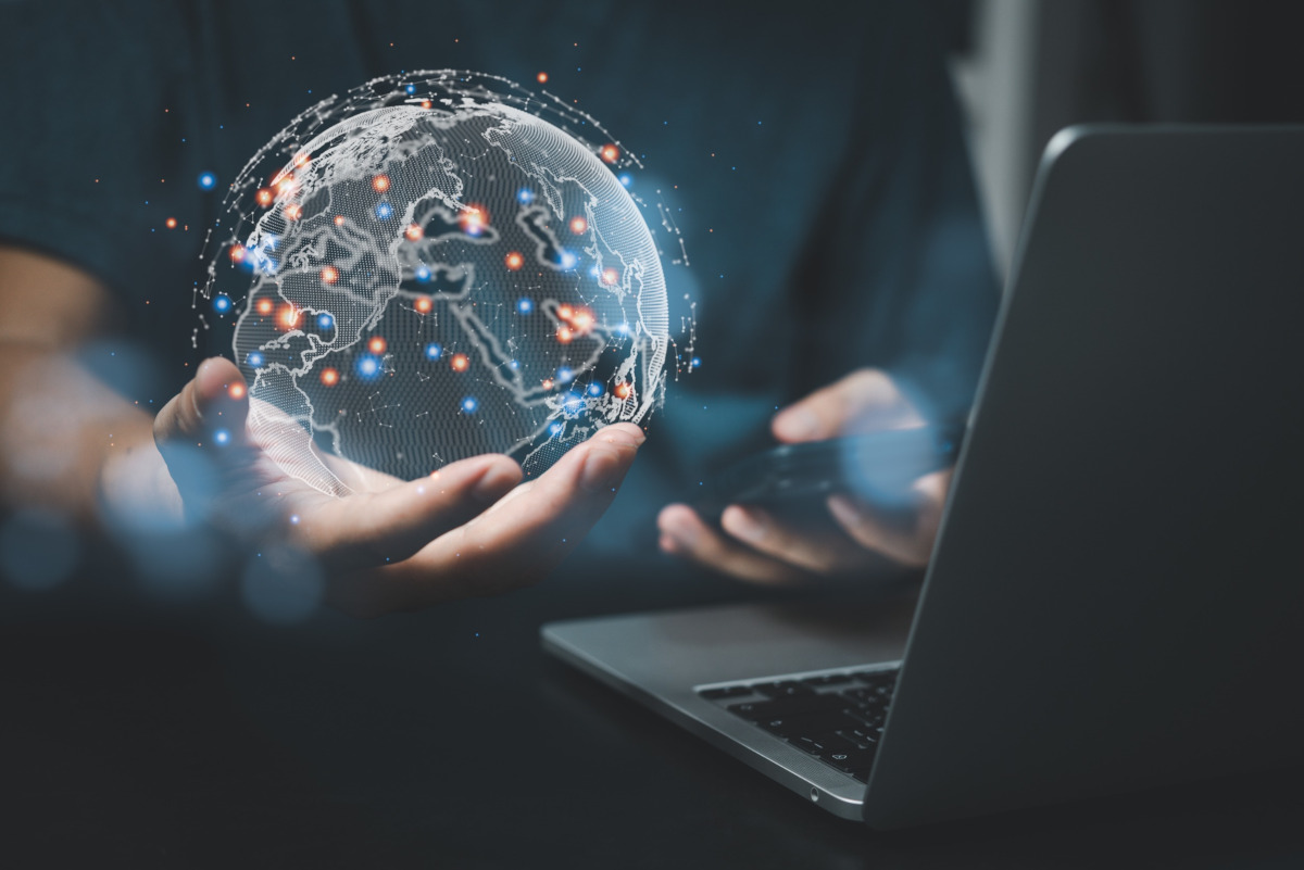 A man holding a digital globe with blue and red dots on the globe